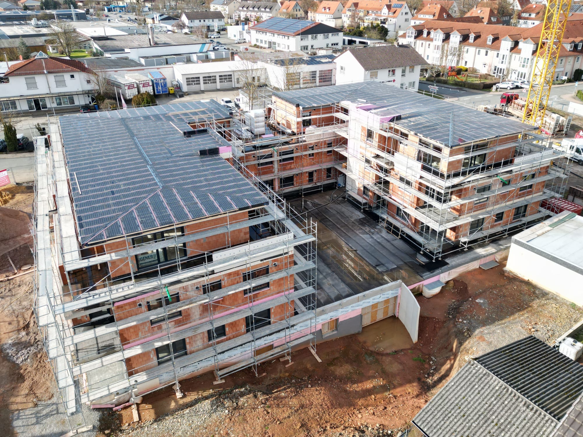 Luftaufnahme einer Wohnbaustelle von Dinger Immobilien in Bad Arolsen mit eingerüsteten Mehrfamilienhäusern im Rohbau