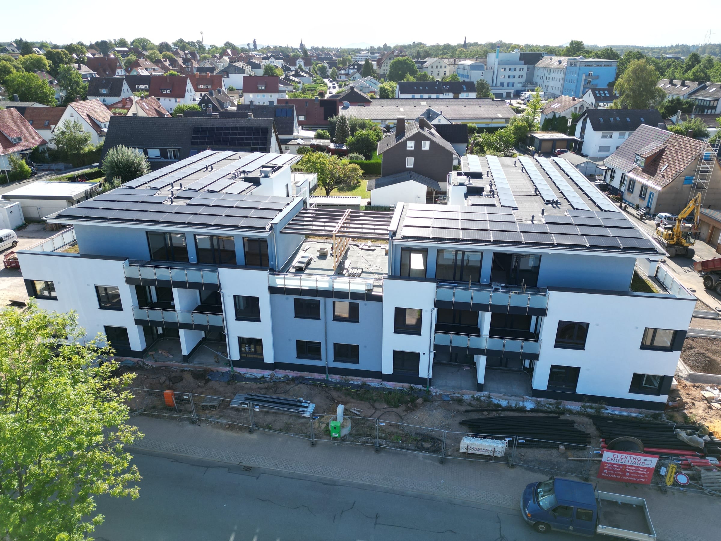 Straßenseite des Wohnprojekts in Bad Arolsen mit fertiger Fassade, Balkonen mit Glasbrüstung und Photovoltaik auf dem Dach